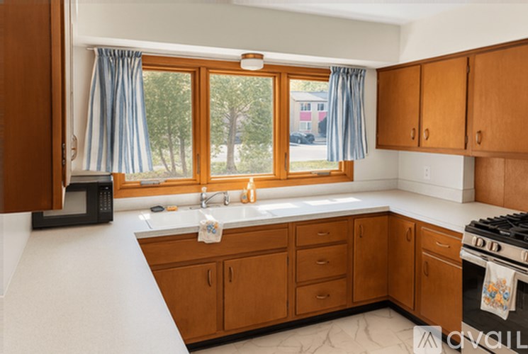 A kitchen with wooden cabinets and a black microwave.