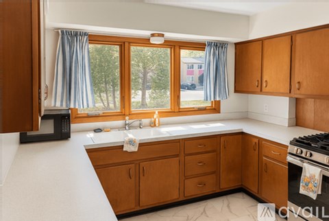 A kitchen with wooden cabinets and a black microwave.