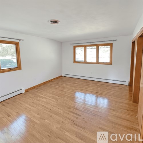 A room with wooden flooring and a window with blinds.