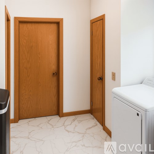 A room with two wooden doors and a white bed.
