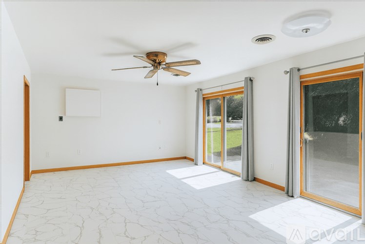 A room with a ceiling fan and sliding glass doors.