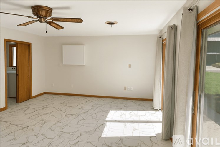 A room with a ceiling fan and a marble floor.