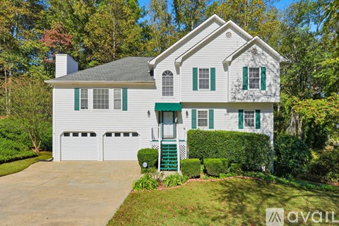 A white house with green shutters and a green awning.