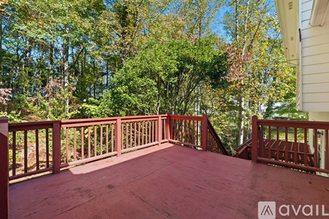 A wooden deck with a railing and trees in the background.