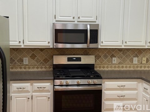 A kitchen with white cabinets and a stainless steel microwave above the stove.