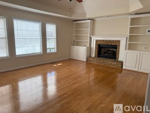A living room with a fireplace and wooden floors.