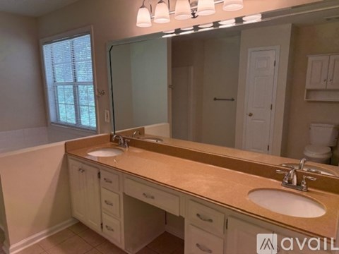 A bathroom with a vanity, sink, mirror, and a window.