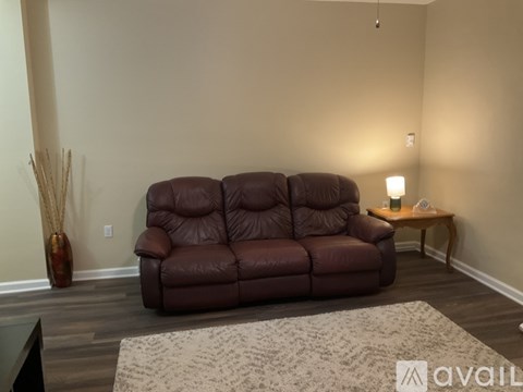 A brown leather sofa sits in a living room with a small table and a vase.