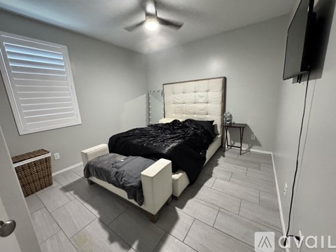 A bedroom with a bed, a ceiling fan, and a television.