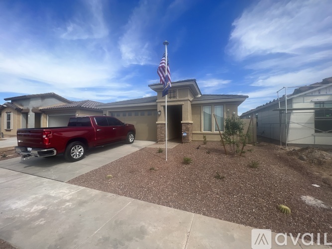 A red pickup truck is parked in front of a house with an American flag on the roof.