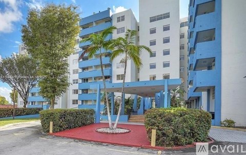 A modern building with a red entrance area and a palm tree in front.