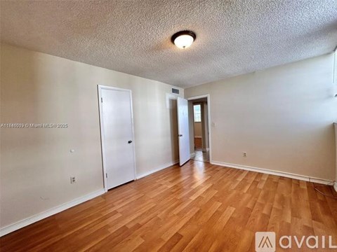 A room with wooden floors and two doors.