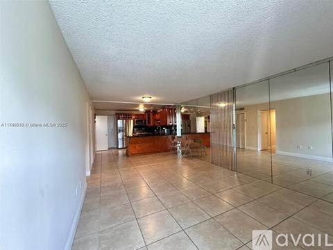 A spacious living room with a kitchen in the background.