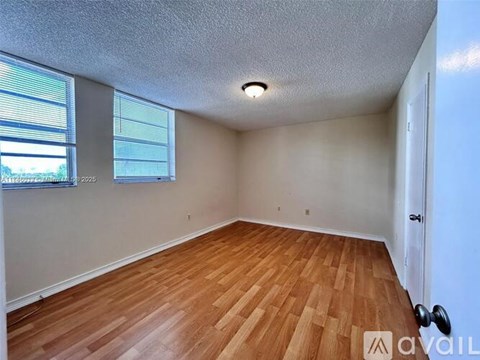 A room with wooden flooring and a window with blinds.