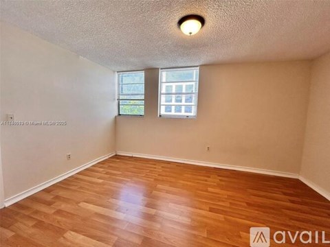 A room with wooden flooring and a window with blinds.