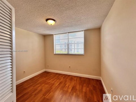 A room with wooden floors and a window with blinds.