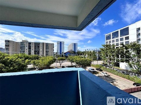 A view from a balcony overlooking a parking lot and buildings.