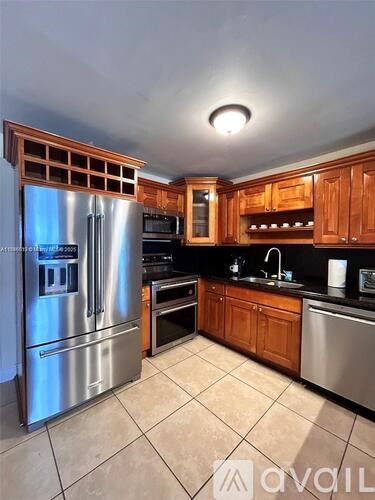 A kitchen with a stainless steel refrigerator and wooden cabinets.