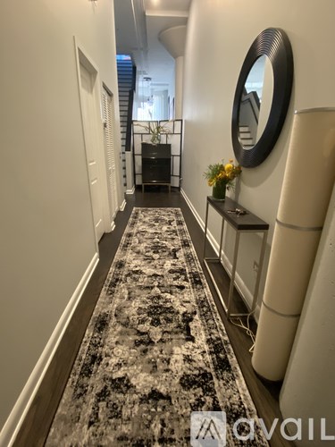 A hallway with a rug on the floor and a mirror on the wall.