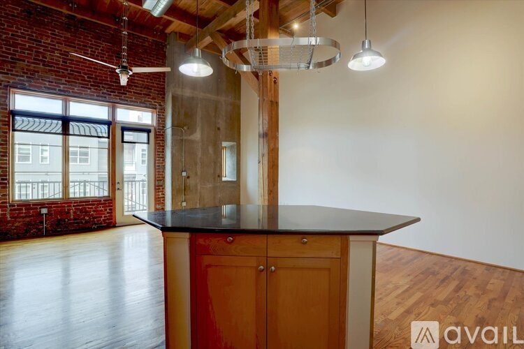 A large, empty room with a black countertop and wooden floors.