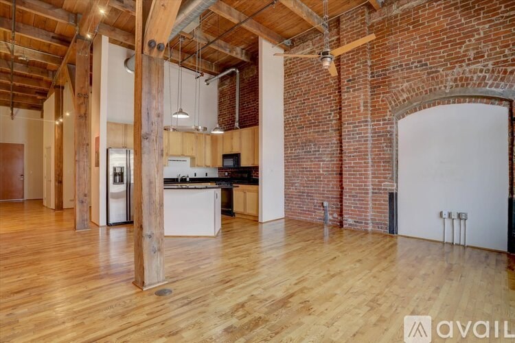 A spacious room with wooden floors and exposed brick walls.