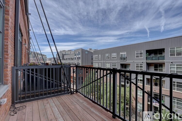 A balcony with a black railing and a wooden floor.