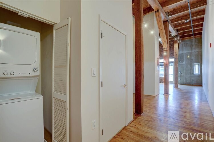 A white washer and dryer in a laundry room with a white door and wooden floors.