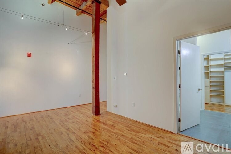 A room with wooden floors and a white wall with a door on the right side.