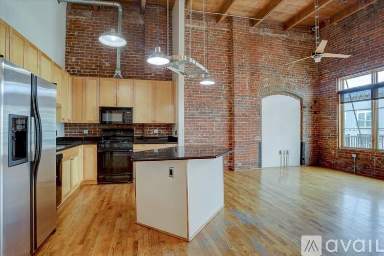 A kitchen with wooden floors and a brick wall.