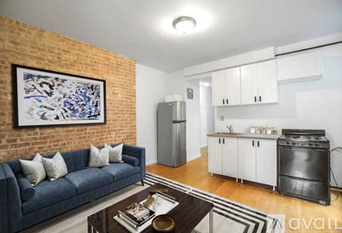A living room with a blue couch and a brick wall.