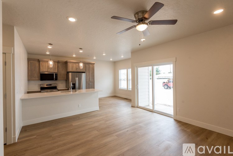 A spacious living room with a ceiling fan and sliding glass doors.
