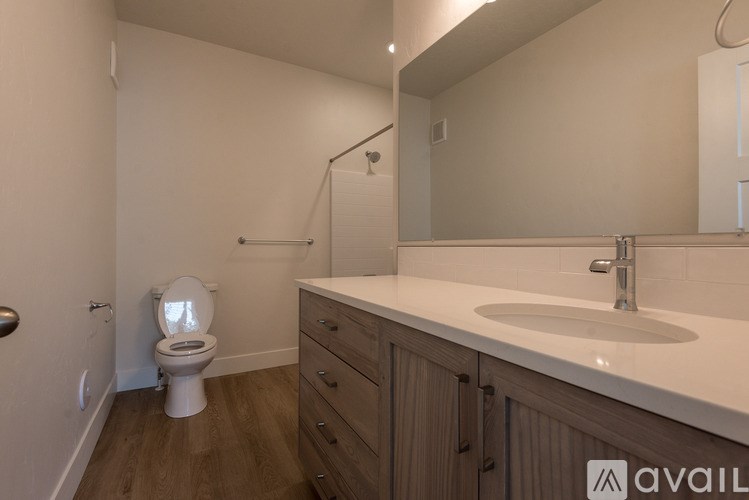 A bathroom with a toilet, sink, and mirror.