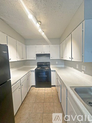 A kitchen with white cabinets and a black fridge.