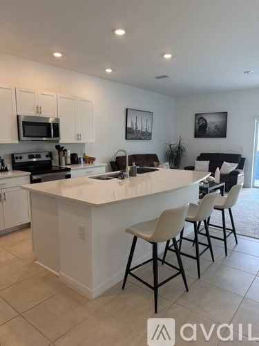 A kitchen with white cabinets and a white island with four chairs.