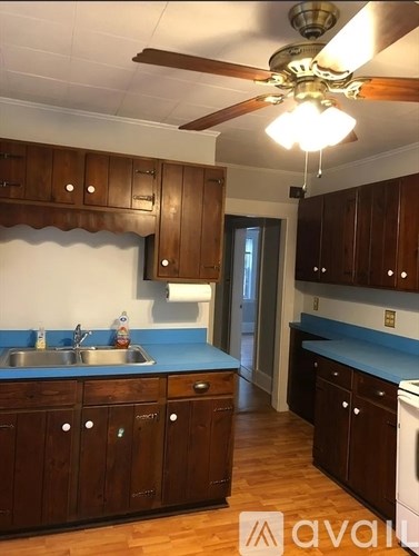 A kitchen with wooden cabinets and a ceiling fan.