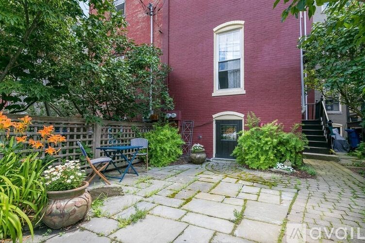 A red brick house with a patio and a bench.
