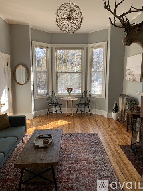 A living room with a couch, chairs, and a rug.