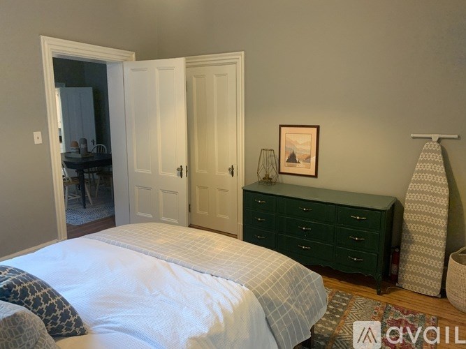 A bedroom with a bed, dresser, and a picture on the wall.