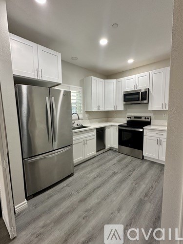 A kitchen with a stainless steel refrigerator and white cabinets.