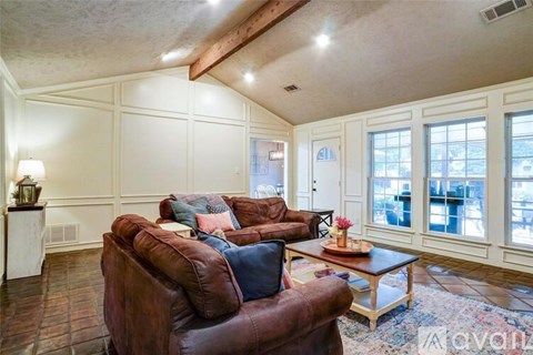 A living room with brown leather chairs and a wooden coffee table.