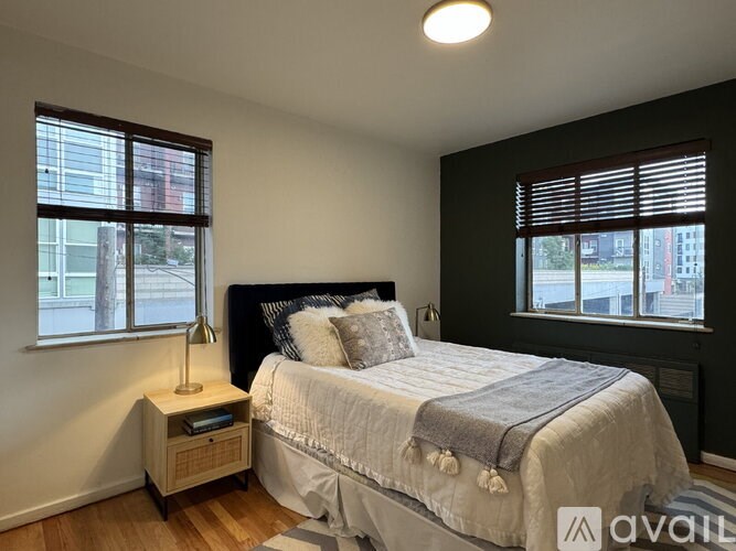 A bedroom with a bed, nightstand, and window.