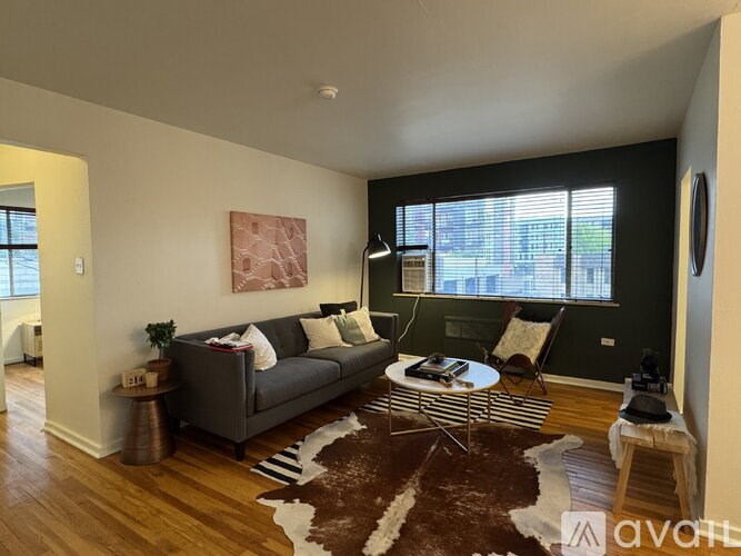 A living room with a grey couch, a coffee table, and a cowhide rug.