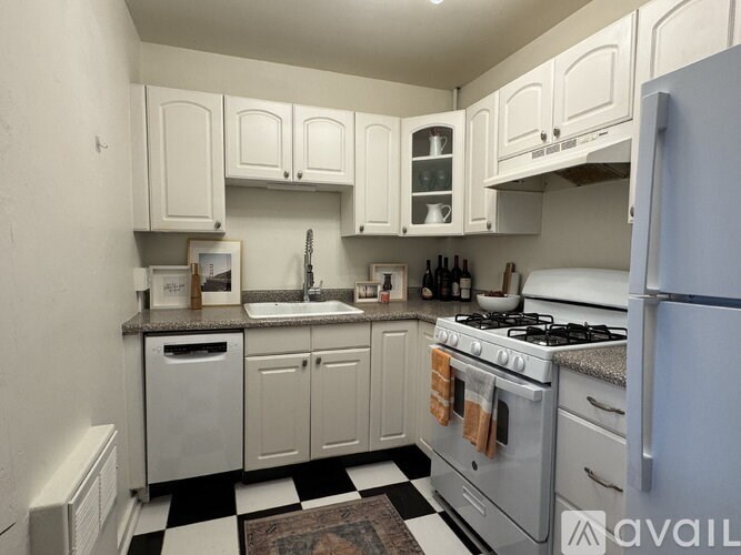 A kitchen with white cabinets and a black and white checkered floor.