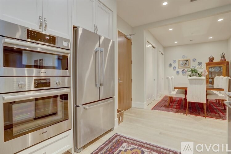 A kitchen with a stainless steel refrigerator and oven, and a dining area with a table and chairs.
