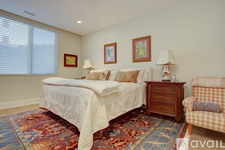 A bedroom with a bed, two lamps, a couch, and a rug.