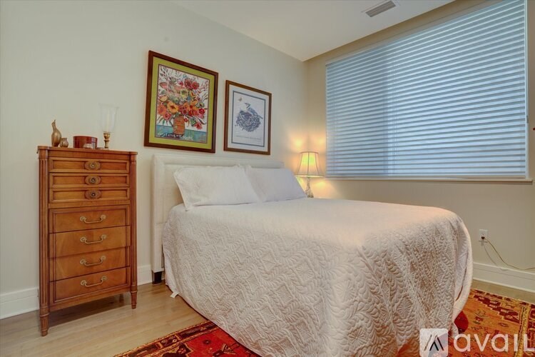 A bedroom with a bed, dresser, and two pictures on the wall.