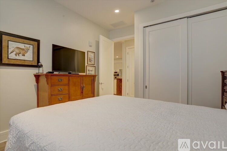 A bedroom with a large bed, a wooden dresser, and a television.