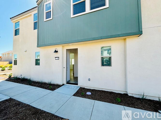 A modern two-story building with a green and white exterior and a front door entrance.