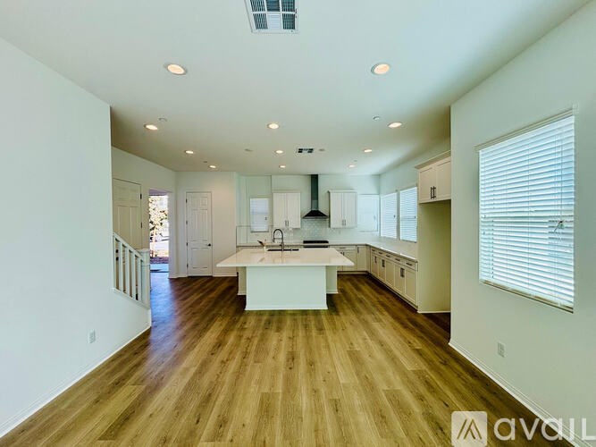 A modern kitchen with wooden floors and white cabinetry.