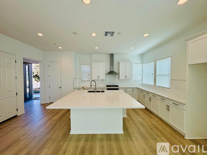 A spacious kitchen with a center island and wooden flooring.